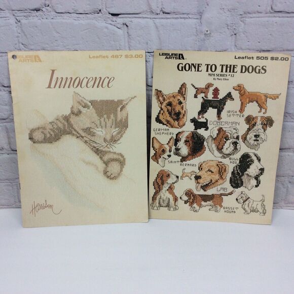 Leisure Arts Innocence & Gone To The Dogs Cross Stitch Pattern Booklets Set of 2 - Picture 1 of 10